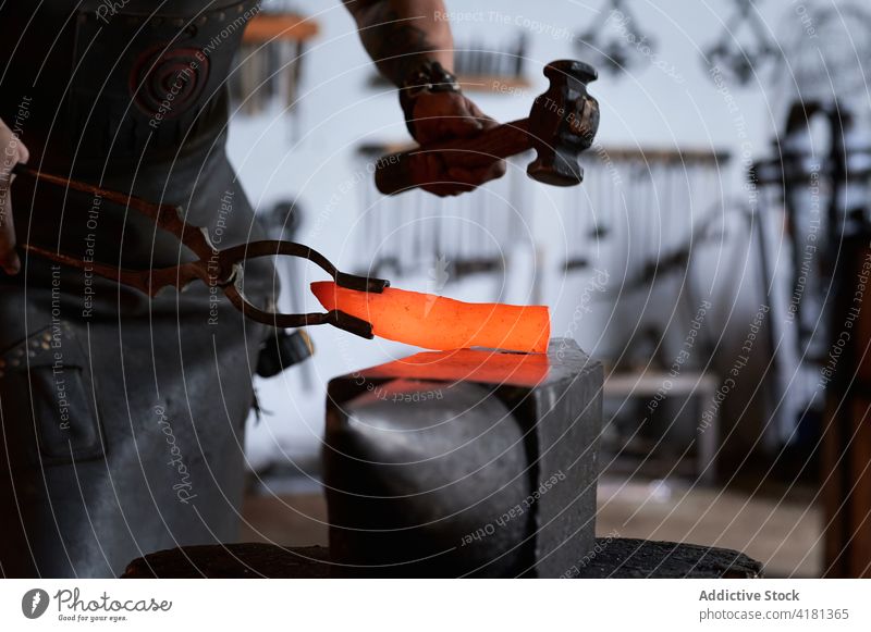 Anonymer junger Schmied, der Metall im Ofen erhitzt Mann erwärmen Schmelzofen schmieden Hufschmied Metallbearbeitung Beruf Werkstatt Arbeit Schmiede männlich