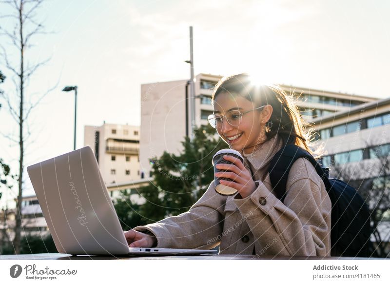 Fröhliche Studentin bei der Arbeit am Laptop im Stadtpark Frau Schüler Zahnfarbenes Lächeln Park Anweisung heiter benutzend Campus Apparatur Pause Kaffee
