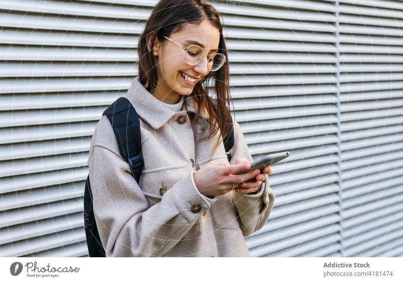 Crop glückliche Frau mit Smartphone auf der Straße Browsen Zahnfarbenes Lächeln Bürgersteig Surfen Funktelefon Gerät benutzend sorgenfrei Inhalt Apparatur