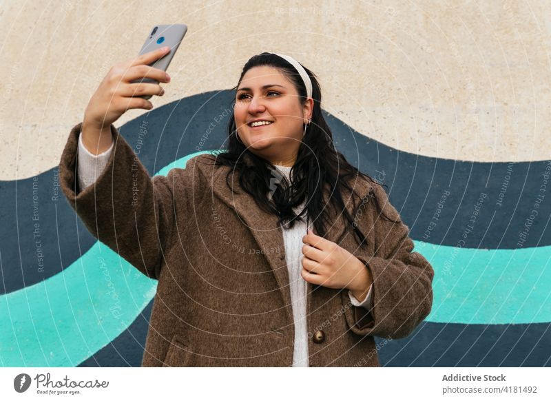 Lächelnde Frau nimmt Selfie auf Smartphone im Freien Moment Gedächtnis heiter benutzend Apparatur Gerät Multimedia modern Stil Headset Funktelefon