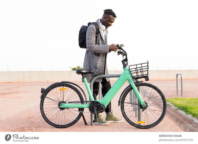 Schwarzer Manager nutzt Fahrradpark-Applikation auf Smartphone in der Stadt Arbeiter Anwendung parken zuschauend Internet Mann Großstadt benutzend Apparatur