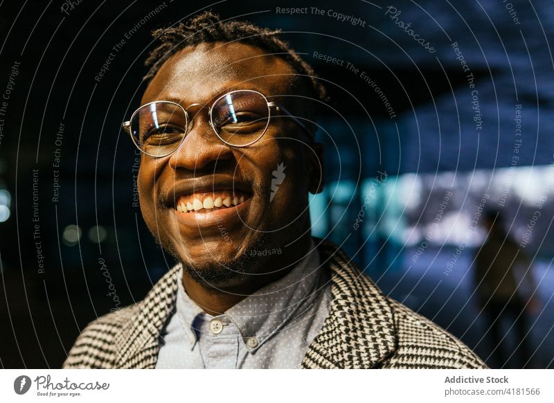 Glücklicher schwarzer Manager mit Brille in der nächtlichen Stadt Mitarbeiter Büro formal Stil Mann Nacht Porträt Lächeln Accessoire nachdenklich nachdenken