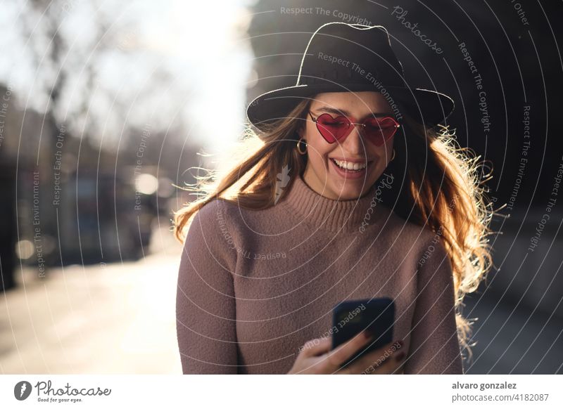 Junge Frau benutzt ihr Mobiltelefon im Freien. Mobile Telefon urban Smartphone sozial Medien Sombrero Mitteilung Sonnenbrille Funktelefon eine selbstbewusst