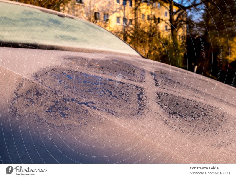Auto mit Raureif und Frost in Morgensonne vor Mehrfamilienhaus. Autofenster Motorhaube glitzer glitzern morgenlicht Sonnenaufgang kalt PKW Fahrzeug Menschenleer