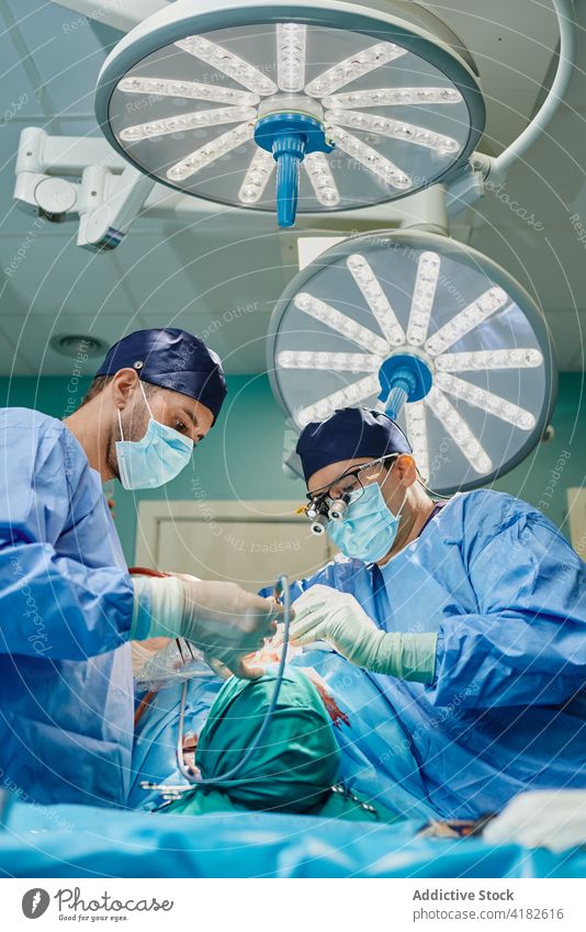 Anonyme junge Ärztin, die dem Chirurgen bei einer Nasenkorrektur hilft Männer Chirurgie Assistent Operationssaal Instrument Nasenplastik steril Feld Klinik