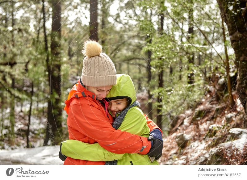 Fröhliche Geschwister, die sich im verschneiten Wald umarmen Geschwisterkind Umarmung Zusammensein Lächeln Glück warme Kleidung Winter rela Freund friedlich