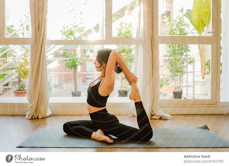 Flexible Frau, die eine einbeinige Königstaube zu Hause vorführt üben Yoga Dehnung beweglich Meerjungfrau-Pose Wellness Gesunder Lebensstil Vitalität heimwärts