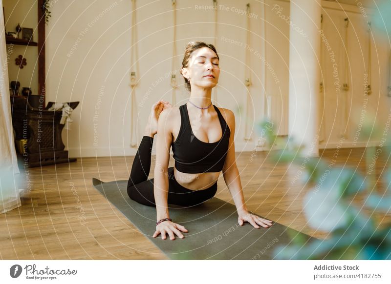 Achtsame Frau zeigt Königskobra-Pose zu Hause Yoga Dehnung Konzentration üben Gesunder Lebensstil Augen geschlossen Backend beweglich Energie heimwärts Wellness