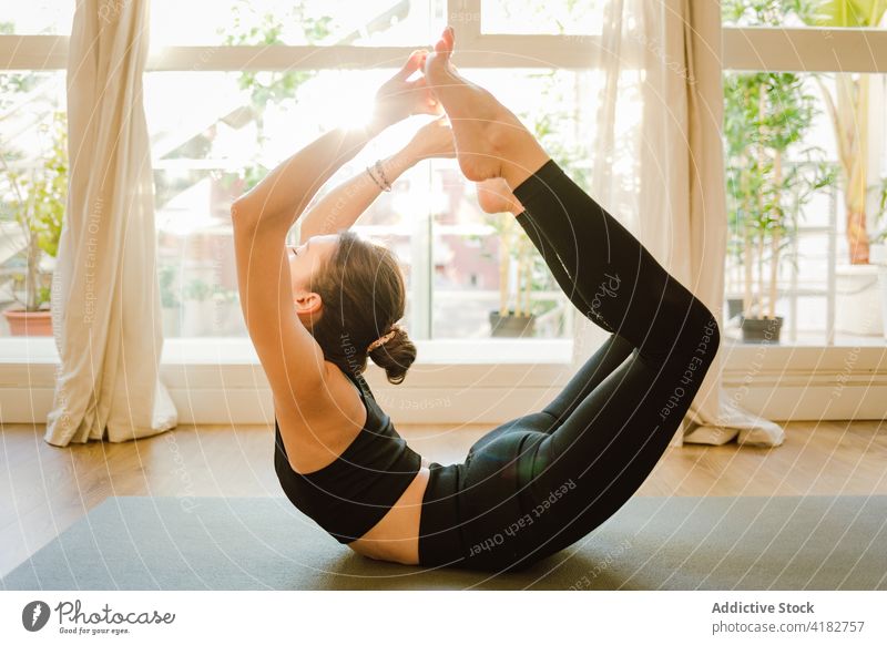Flexible Frau in Bogenstellung auf einer Matte im Haus Yoga beweglich Dehnung üben Augen geschlossen Gesunder Lebensstil Vitalität Achtsamkeit perfekt Barfuß