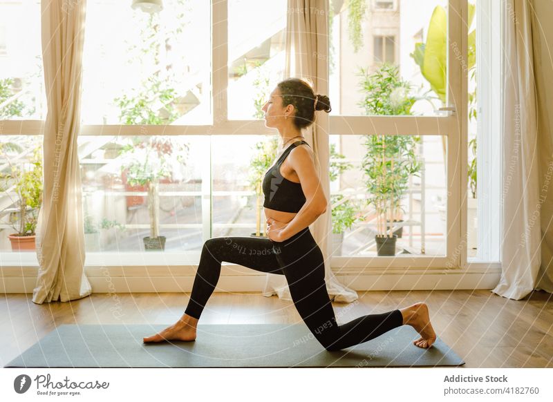 Frau bereitet sich darauf vor, die Pose des Halbmondes auf dem Knie in einem Raum auszuführen Yoga Halbmond-Longe auf Knie üben Wellness Gesunder Lebensstil