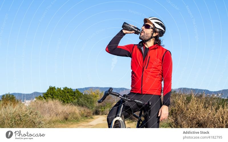 Radfahrer trinkt Wasser nach dem Training auf dem Lande trinken Fahrrad ruhen Pause sportlich Mann aktiv männlich Lifestyle Aktivität Erholung Sport Athlet