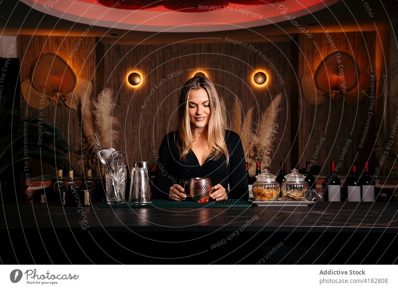 Stilvolle junge Frau bei der Zubereitung eines alkoholischen Cocktails in einer modernen Bar vorbereiten selbstsicher Alkohol selbstbewusst trinken Barkeeper