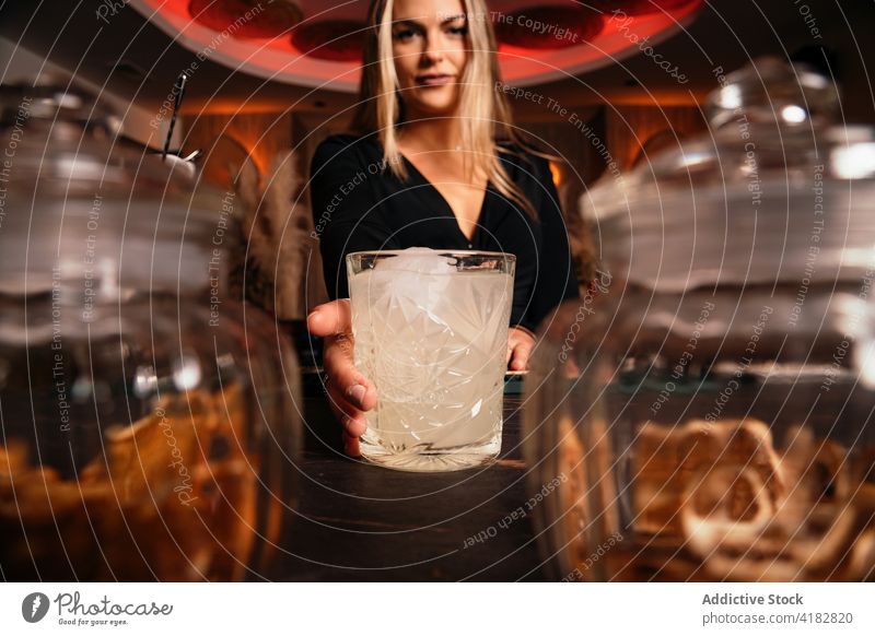 Lächelnde junge Frau serviert erfrischenden Cocktail in einer Bar dienen Barkeeper Alkohol Getränk trinken Inhalt Restaurant Erfrischung lange Haare blond kalt