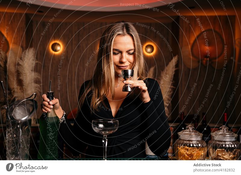 Selbstbewusste junge Frau riecht an einem alkoholischen Getränk bei der Zubereitung eines Cocktails in einer Bar riechen Alkohol Jigger Barkeeper vorbereiten