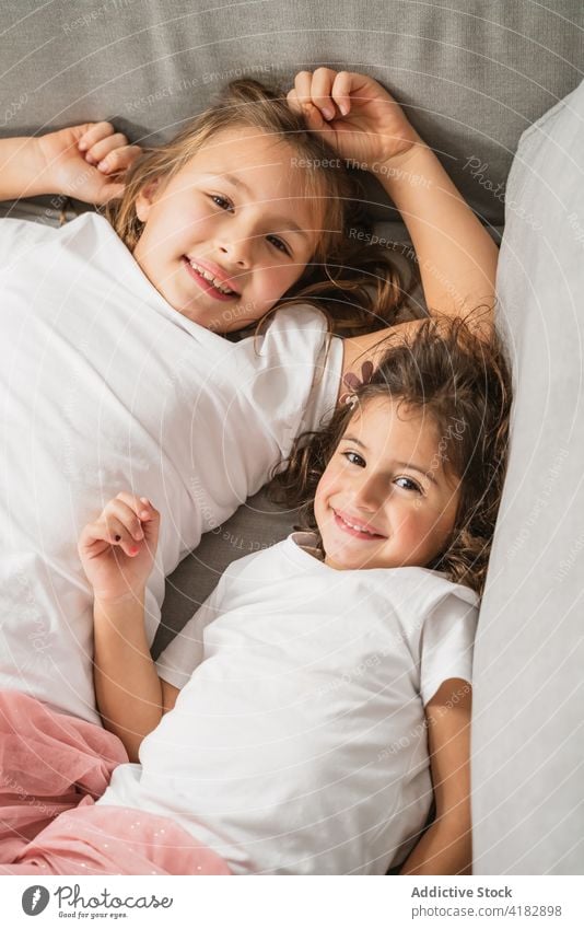 Zufriedene Schwestern auf gemütlichem Sofa Mädchen heiter Glück kindisch Spaß haben spielerisch Kinder Inhalt Glee Freude Geschwisterkind Kindheit lässig