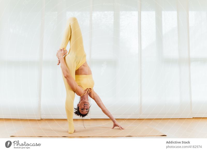 Flexible Frau, die ihren Körper während einer Yoga-Sitzung dehnt Wegbiegung Dehnung Körperhaltung Übung beweglich Anmut positionieren Fokus Arme hochgezogen
