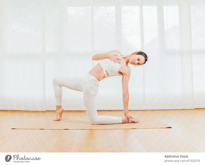 Frau übt sich auf einer Matte im Ausfallschritt Backend halbmondförmiger Ausfallschritt beweglich Dehnung Yoga Körperhaltung auf Zehenspitzen Spannung Fokus