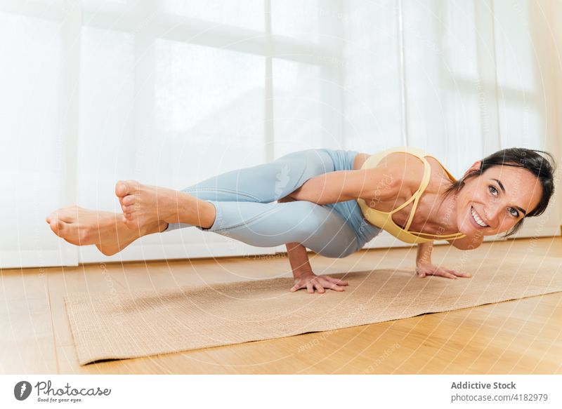Positive Sportlerin beim Üben der Achter-Winkel-Position Frau Yoga Asana Achtwinkel Optimist fortgeschritten Gleichgewicht Gesunder Lebensstil Wellness