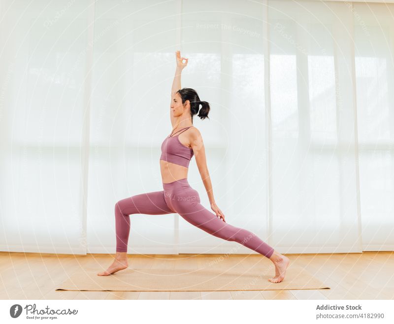 Sportliche Frau beim Crescent Lunge zur Förderung der Stabilität Yoga halbmondförmiger Ausfallschritt Körperhaltung auf Zehenspitzen positionieren Dehnung