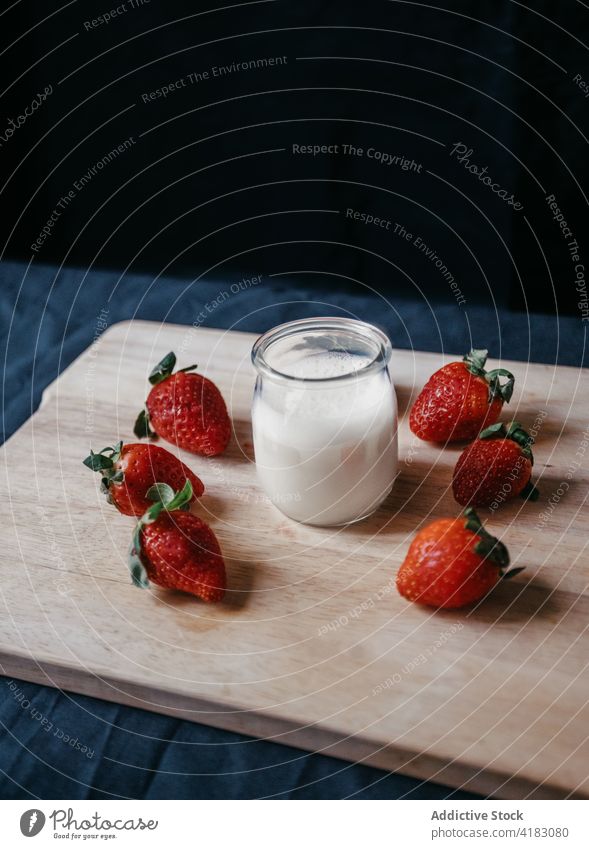Glas Milch neben reifen Erdbeeren auf dem Schneidebrett melken Molkerei Vitamin Protein natürlich Bestandteil süß Smoothie durchsichtig Nährstoff Beeren