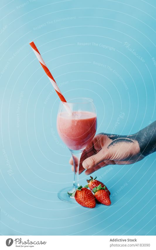 Kropfträger mit einem Glas süßem Erfrischungsgetränk Person Smoothie Erdbeeren gesundes Getränk lecker Vitamin Stroh farbenfroh reif geschmackvoll organisch