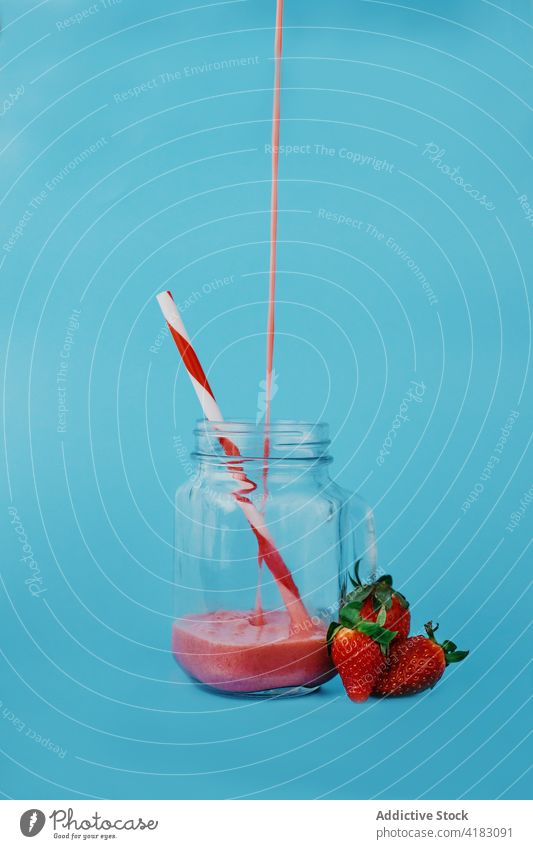 Leckerer Erdbeer-Smoothie im Glas auf blauem Hintergrund Erdbeeren eingießen Vitamin süß Erfrischung lecker Flüssigkeit reif fließen gesundes Getränk