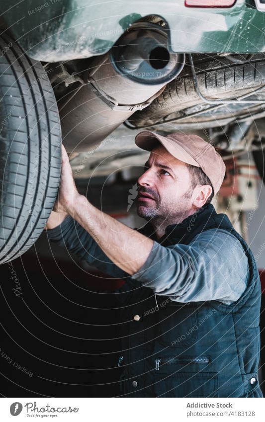 Männlicher Mechaniker prüft Reifen eines Fahrzeugs in einer Werkstatt Meister prüfen Rad Verkehr achtsam Beruf Mann Garage überarbeiten PKW Flugzeugwartung