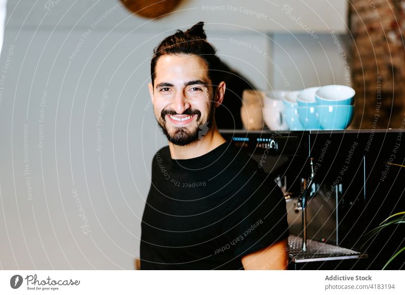 Gut gelaunte Barista, die ein Getränk in einer Kaffeemaschine zubereitet vorbereiten Maschine Portafilter Café heiter trinken Mann männlich Barkeeper Arbeit Job