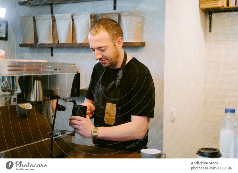 Inhalt Barista bereitet Kaffee in Kaffeemaschine zu melken Peitsche Mann vorbereiten Maschine trinken Café männlich Kaffeehaus Kantine Krug Kannen Personal