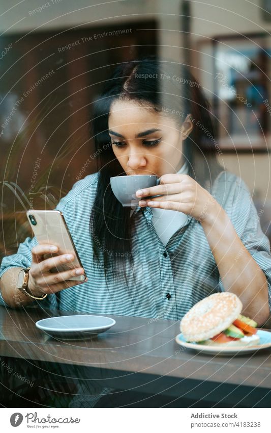 Frau trinkt eine Tasse Kaffee und benutzt ein Handy Funktelefon Technik & Technologie Telefon Mobile Kaffeehaus Glück Internet Café Drahtlos Menschen Person