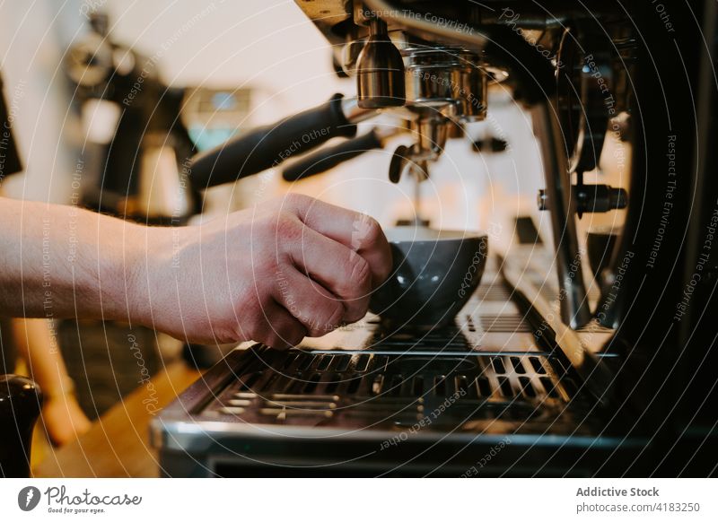 Crop Barista bereitet heißen Kaffee in einem Café zu Kaffeemaschine vorbereiten Kaffeehaus Maschine Tasse trinken Mann modern männlich professionell Getränk
