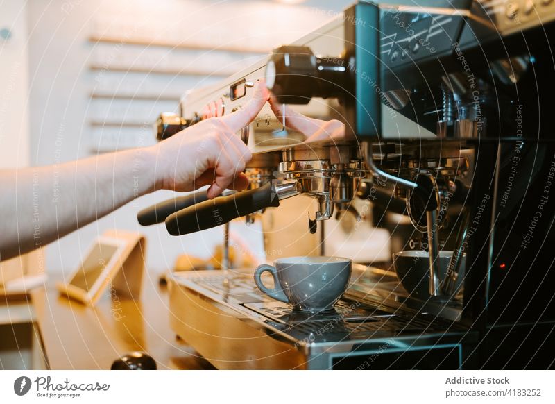 Crop Barista bereitet heißen Kaffee in einem Café zu Kaffeemaschine vorbereiten Kaffeehaus Maschine Tasse trinken Mann modern männlich professionell Getränk