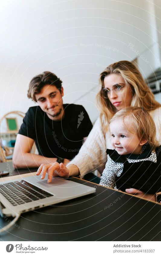 Familie schaut sich zu Hause gemeinsam einen Film auf dem Laptop an zuschauen Kleinkind heimwärts Wochenende Paar wenig Kind Tisch Zusammensein Bonden sitzen