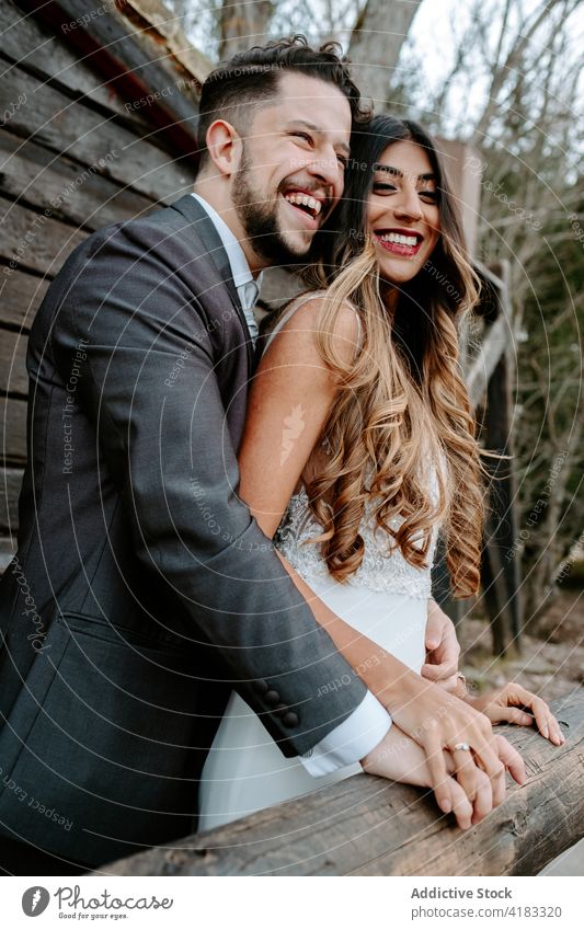 Positives junges multiethnisches Brautpaar, das sich im Wald an den Händen hält und lacht Paar Jungvermählter Lachen heiter kuscheln Liebe romantisch