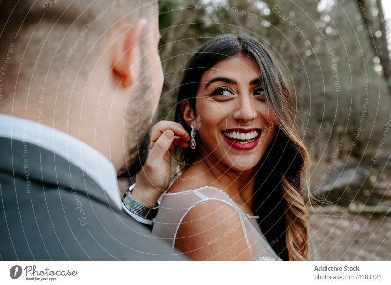 Positives junges multiethnisches Brautpaar, das sich im Wald an den Händen hält und lacht Paar Jungvermählter Lachen heiter kuscheln Liebe romantisch