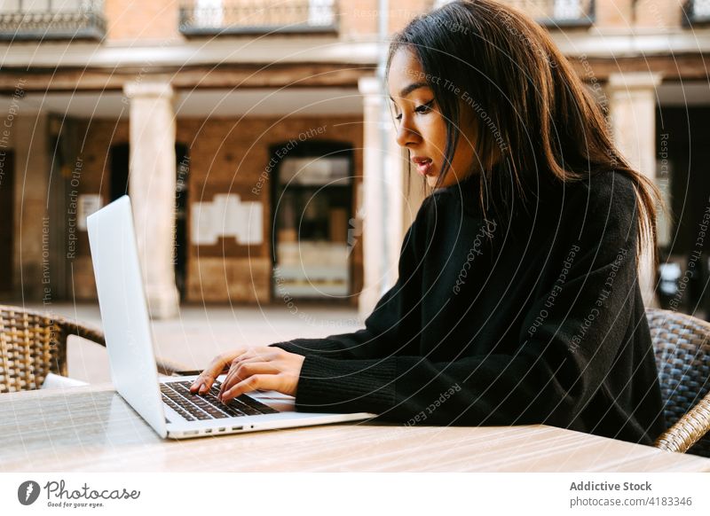 Moderne Frau mit Laptop am Tisch auf der Straße freiberuflich Café Bürgersteig Netbook Surfen Zeitgenosse abgelegen Computer Anschluss Tippen online Beruf