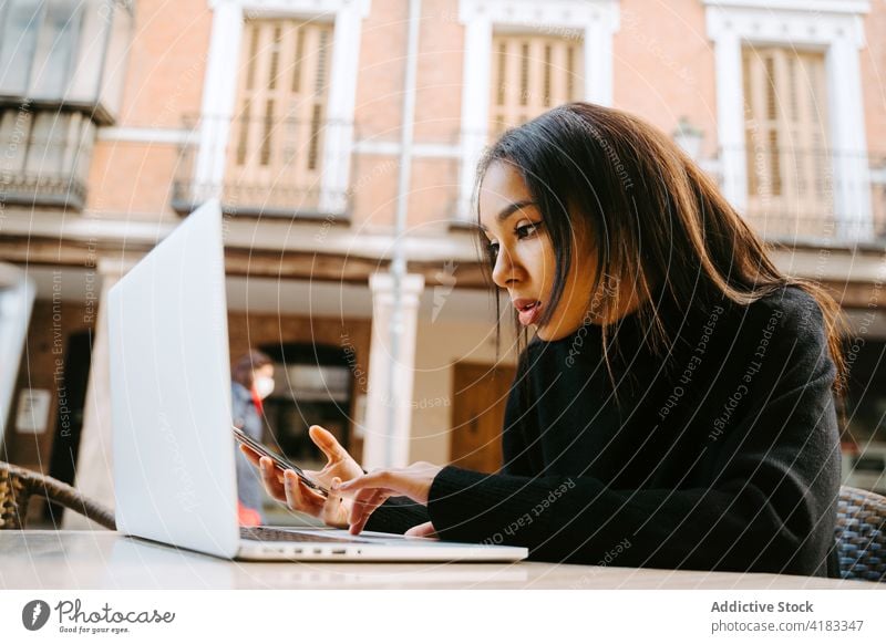 Moderne Frau mit Laptop am Tisch auf der Straße freiberuflich Café Bürgersteig Netbook Surfen Zeitgenosse abgelegen Computer Anschluss Tippen online Beruf