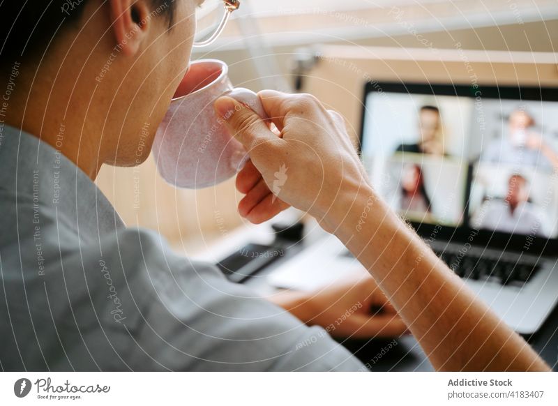 Geschäftsmann führt Videogespräch auf Laptop Videoanruf Tagung Coronavirus Arbeit heimwärts Video-Chat neue Normale trinken Mann männlich online Mitarbeiter