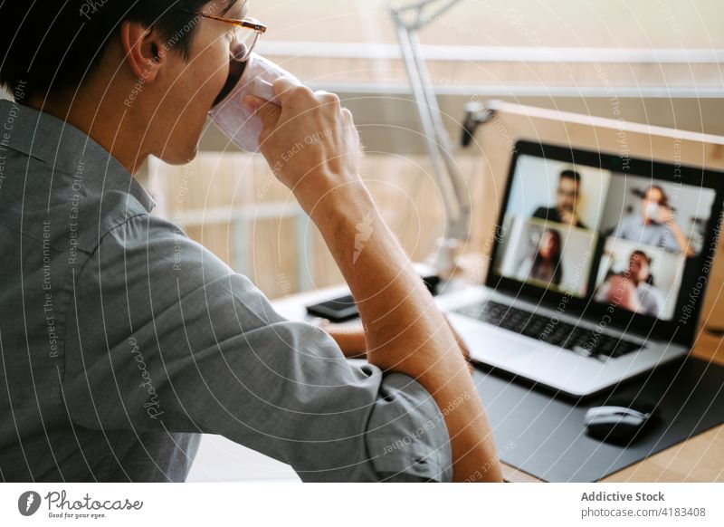 Geschäftsmann führt Videogespräch auf Laptop Videoanruf Tagung Coronavirus Arbeit heimwärts Video-Chat neue Normale trinken Mann männlich online Mitarbeiter
