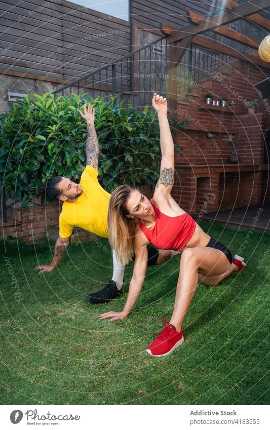 Ein sportlicher Mann und eine Frau machen Yoga in der Pose des gedrehten halbmondförmigen Ausfallschrittes auf den Knien Sportlerin üben beweglich Dehnung