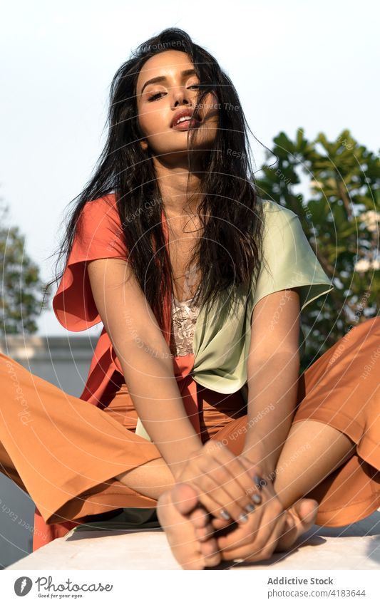 Stilvolle Brünette ruht sich auf der Terrasse aus Frau Mode farbenfroh brünett jung Barfuß sinnlich ruhen sich[Akk] entspannen ethnisch trendy tausendjährig