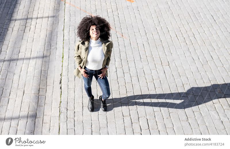 Zufriedene junge afroamerikanische Frau auf der Straße stehend expressiv zufrieden Straßenbelag Stil Glück Lächeln Inhalt genießen Großstadt Freude schwarz