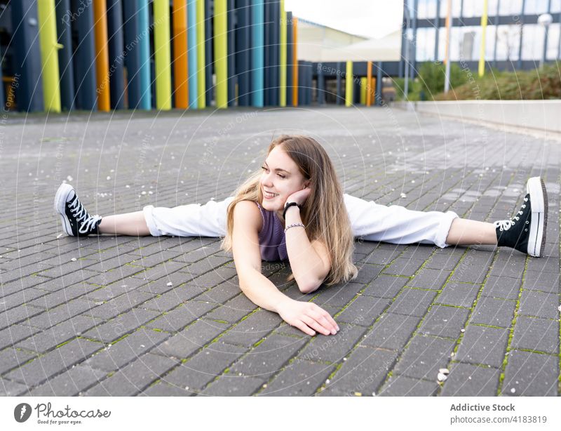 Zufriedene junge Frau beim Spagat auf dem Bürgersteig auf der Straße Split beweglich Dehnung sportlich Energie gymnastisch Fähigkeit sich auf die Hand lehnen