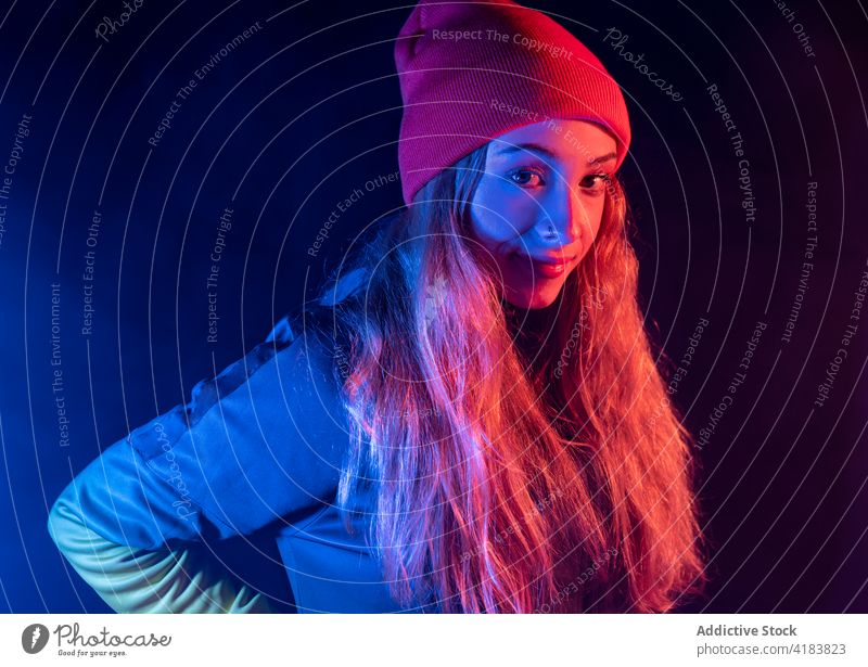 Junge weibliche Millennials stehen in einem verrauchten Neonraum Frau Stil neonfarbig Rauch selbstbewusst Vorschein Porträt Mode leuchten dunkel jung