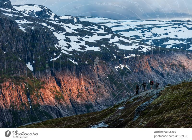 Gesellschaft von Reisenden auf einem felsigen Hügel im Gebirge Menschengruppe Reisender Berge u. Gebirge Sonnenuntergang Wanderer erkunden Hochland Schnee