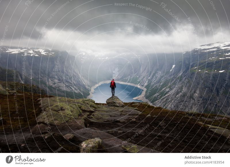 Reisender steht am Rande eines Felsens in den Bergen anonym Saum Formation Abenteuer Rucksack sorgenfrei Freiheit genießen trolltunga Norwegen Urlaub malerisch