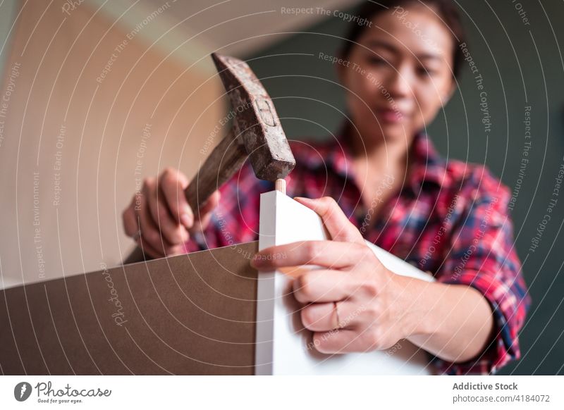 Asiatische Frau beim Zusammenbau von Möbeln zu Hause versammeln Hammer Dübel nageln hölzern neu heimwärts Fokus ethnisch asiatisch wohnbedingt ernst