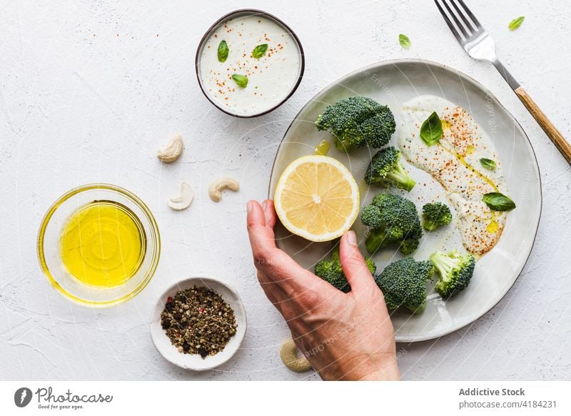Leckerer Brokkoli mit weißer Soße und Zitrone auf dem Teller gesunde Ernährung Speisekarte Vegetarier Vitamin Protein natürlich Tisch Café mischen Gewürz oliv