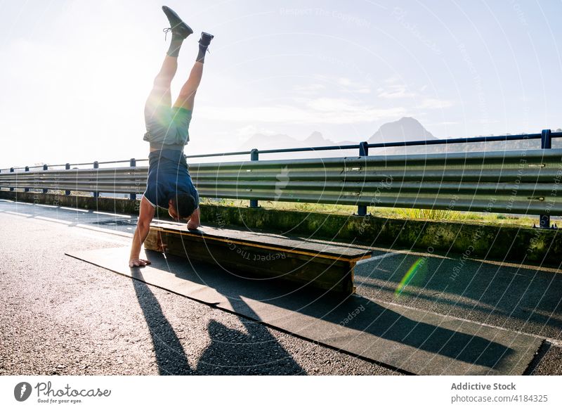 Anonymer behinderter Sportler im Handstand auf einer Brücke im Sonnenschein Athlet Gleichgewicht Training Talent Übung Landschaft Fähigkeit Mann Bank Himmel