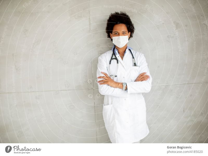 Weiblicher afroamerikanischer Arzt trägt weiße Uniform und schützende Gesichtsmaske Erwachsener Afrikanisch Amerikaner schwarz Klinik Konzept Korona Coronavirus
